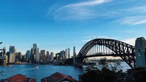 A city skyline with a prominent bridge, modern buildings, and a body of water.