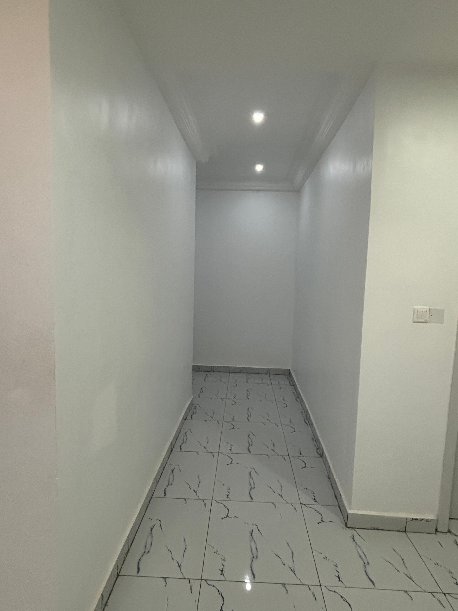 A narrow hallway with white walls and a tiled floor.