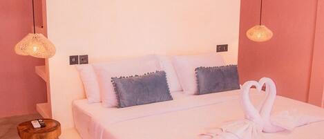 A bedroom with a large bed, two bedside lamps, a bedside table, and a wall-mounted air conditioner.