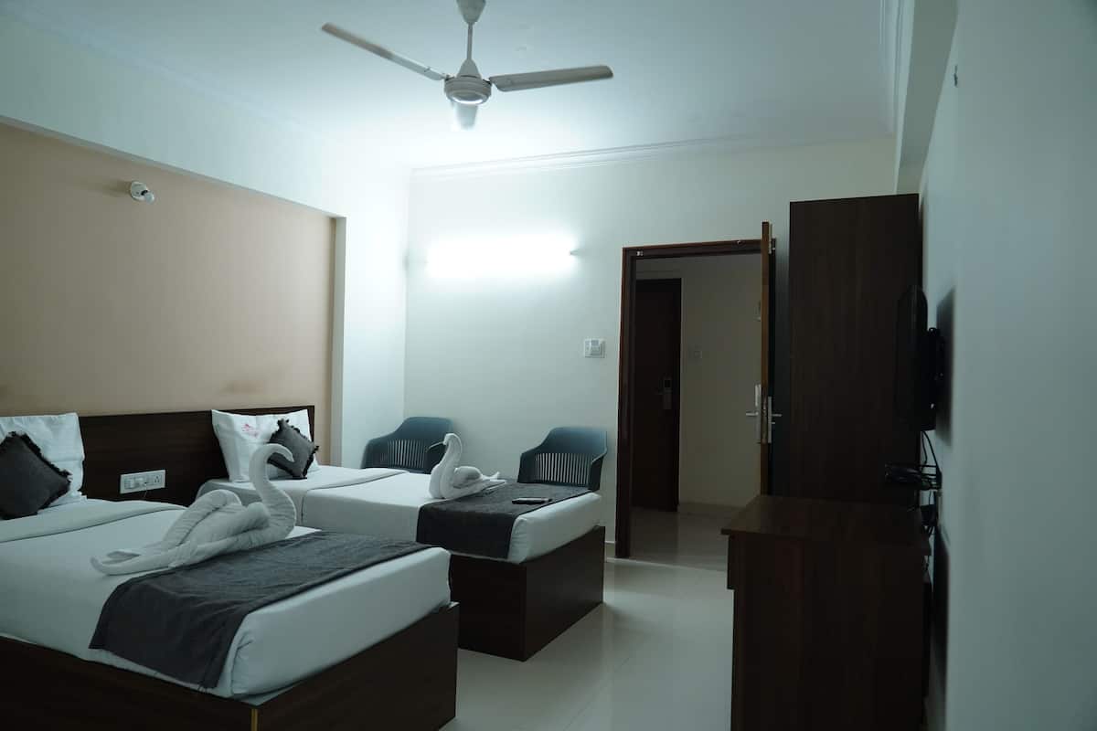 Quarto de hotel com duas camas, um ventilador de teto, uma TV e um guarda-roupa de madeira.