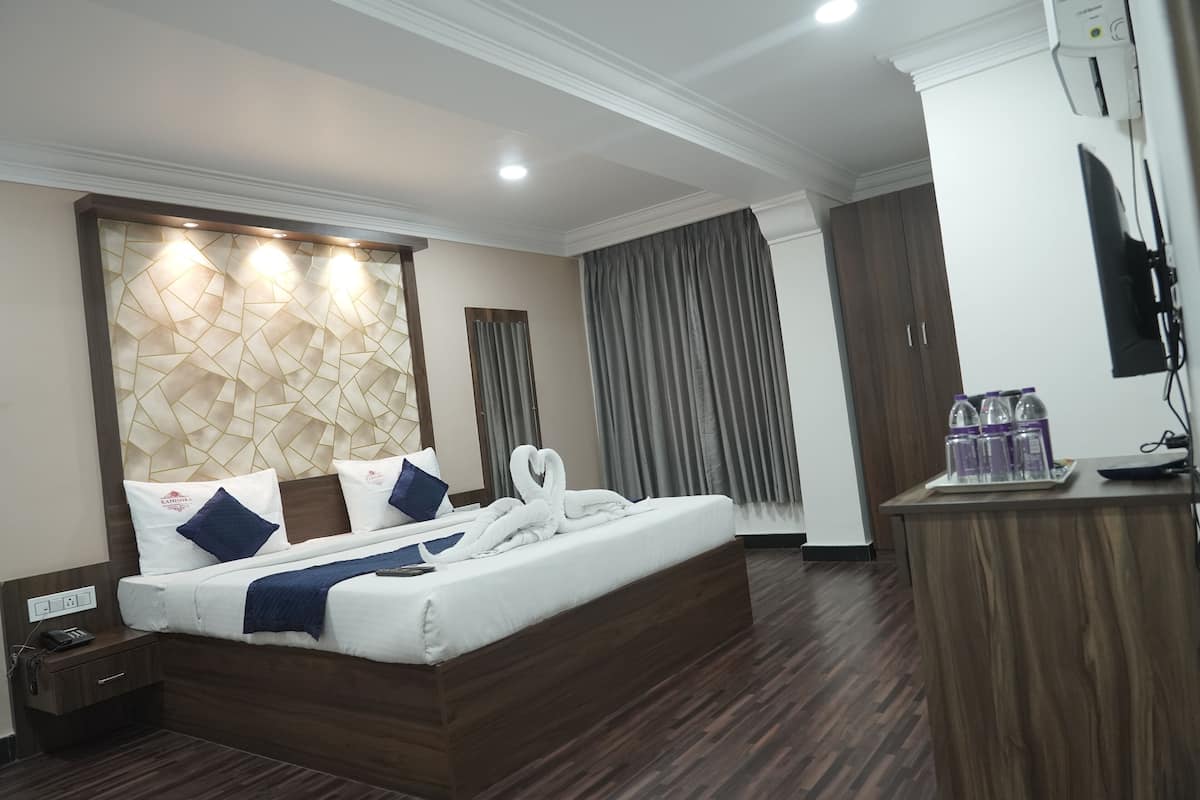 Quarto de hotel com cama, cabeceira de madeira, escrivaninha e televisão de tela plana, além de minibar.