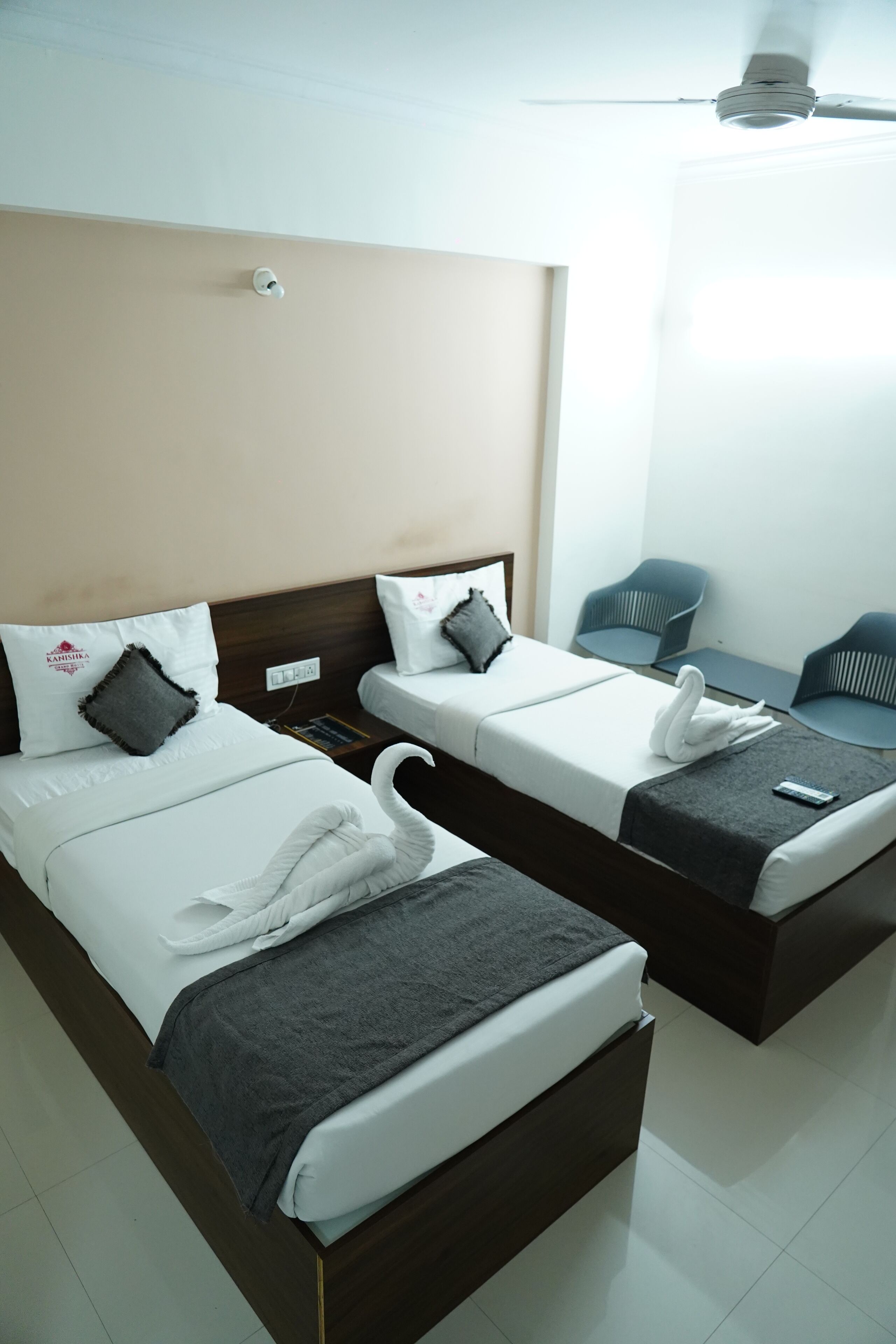A hotel room with two beds, a ceiling fan, and a small table with chairs.