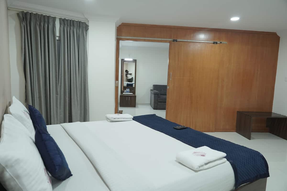 Quarto de hotel com cama, guarda-roupa de madeira, escrivaninha e espelho.