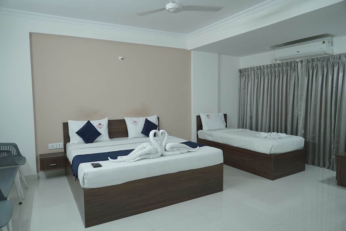 Quarto de hotel com duas camas, um ventilador de teto, um aparelho de ar condicionado e uma cortina cinzenta.