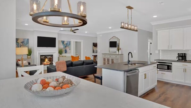 Een moderne keuken met witte kastjes, een centraal eiland met een spoelbak en een eethoek met een witte tafel en stoelen.