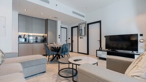 Un salon moderne avec un canapé, une table basse et un téléviseur. Il y a également un coin repas avec des chaises et une table.