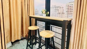 A balcony with two wooden stools, a small table, and a potted plant.