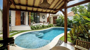 Une piscine surmontée d’une pergola en bois, entourée d’une végétation luxuriante et d’une pelouse bien entretenue.