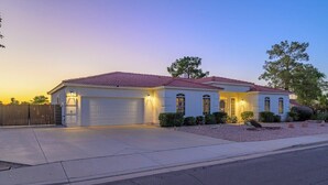 Une maison à deux étages avec un toit recouvert de tuiles rouges, un garage et une cour avant bien entretenue, agrémentée d’un aménagement paysager.