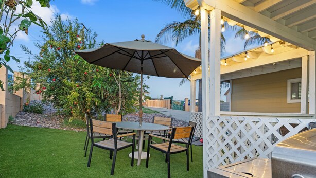 An outdoor patio with a table and chairs, a grill, and a white lattice fence. - Relax & Unwind - Cozy 1 BR w/ Room for 5 Guests (San Diego)