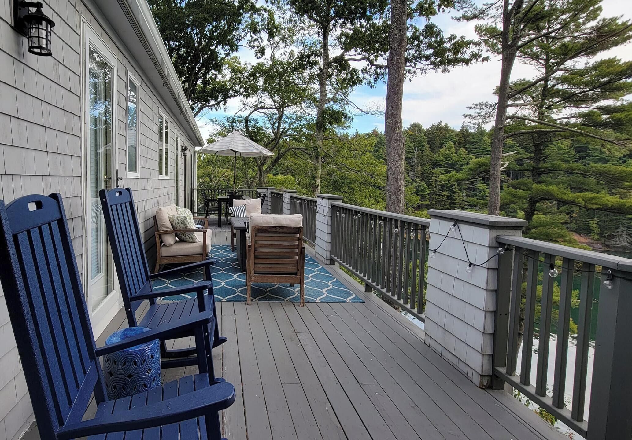 A wooden deck with outdoor furniture, including chairs and a table, and a railing.