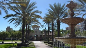 A fountain, palm trees, and a building with arched windows in a courtyard. - Huge Vista Cay Ground Floor (Orlando)