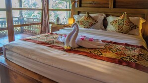 Una cama con un edredón estampado, almohadas y una presentación de toallas.