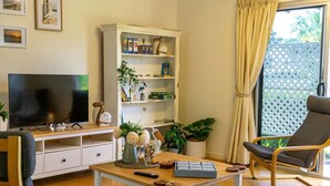 Un soggiorno con televisore, una libreria, un tavolino da caffè e una poltrona.