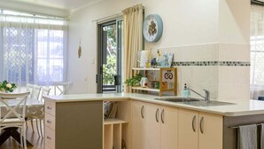 Una cucina compatta con lavandino, pensili e zona pranzo con tavolo e sedie.
