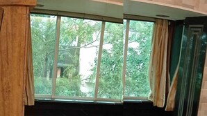 A bedroom with a large window, a wooden desk, and a bed.