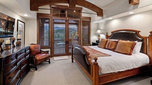 Une chambre spacieuse avec un grand lit, une tête de lit en bois et une vue dégagée grâce à une porte-fenêtre coulissante.