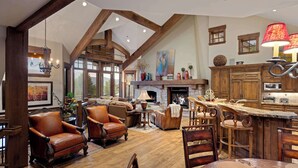 Un vaste espace de vie doté d’une cheminée, de meubles en bois et d’un plafond haut avec des poutres apparentes.