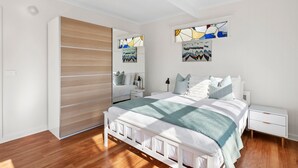 Une chambre à coucher moderne, avec un lit, des tables de chevet, une armoire et des œuvres d’art accrochées aux murs.