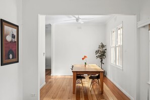 A dining area with a wooden table, chairs, a ceiling fan, and a potted plant.