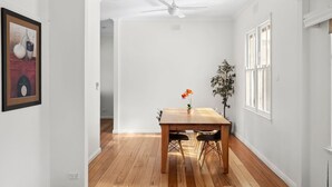 Un coin repas avec une table en bois, des chaises, un ventilateur de plafond et une plante en pot.