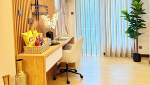Una habitación de hotel moderna con un mostrador de recepción de madera, una silla blanca, una planta en maceta y un ventanal con persianas.