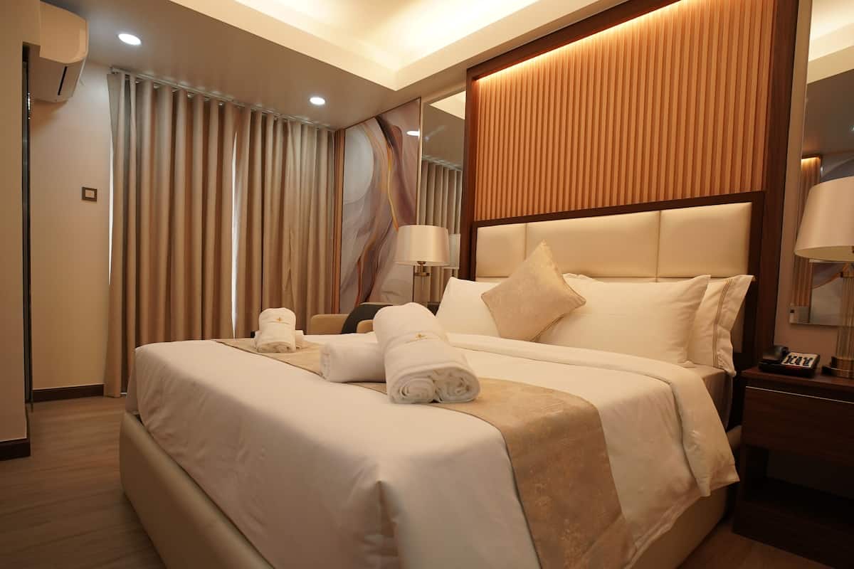Une chambre d’hôtel avec un grand lit, une table de chevet avec une lampe et un miroir.
