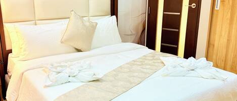 Una cama bien tendida con sábanas blancas y una toalla decorativa.