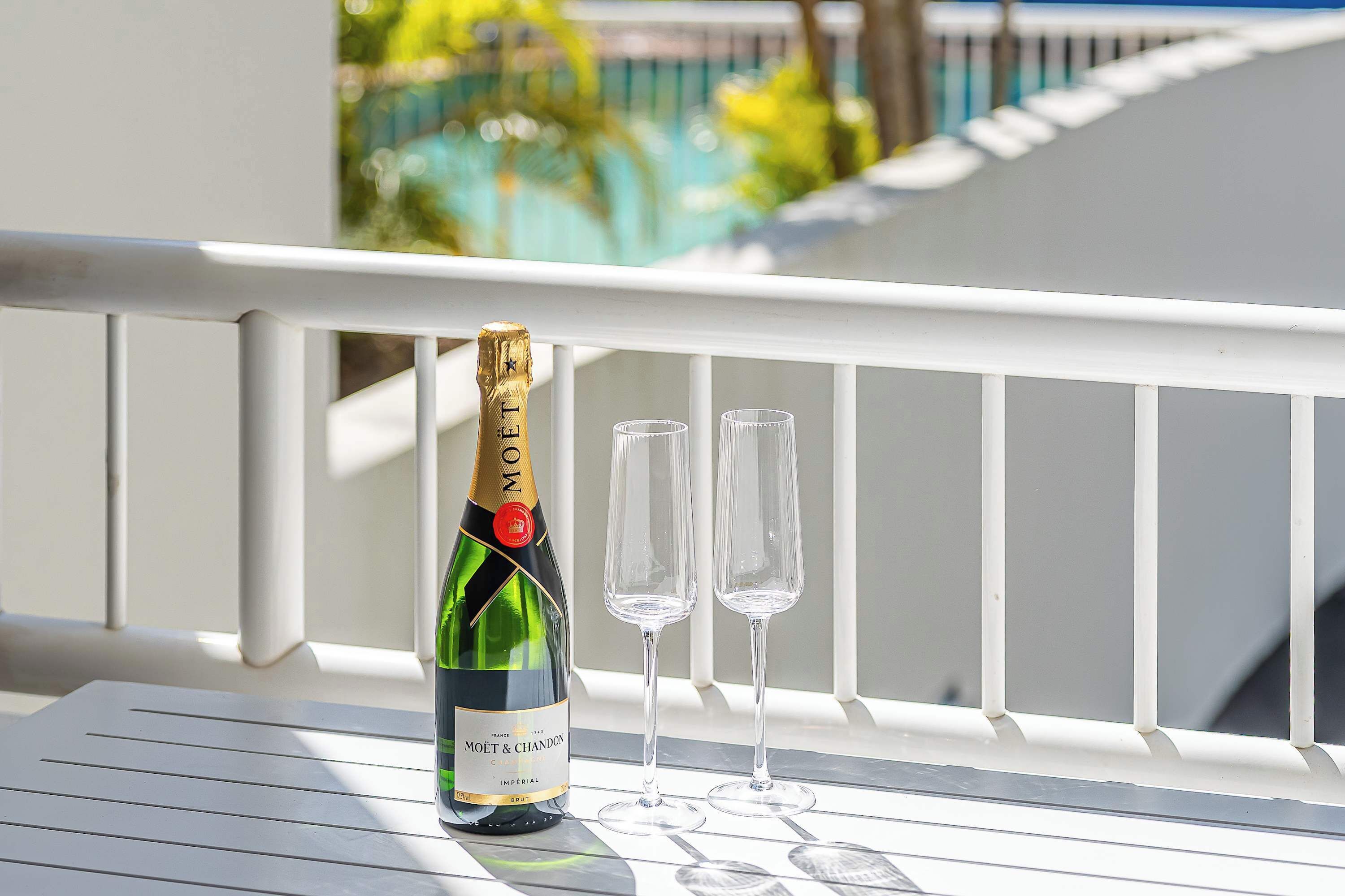 Eine Flasche Moët & Chandon Champagner und zwei Gläser auf einer weißen Balkonbrüstung.