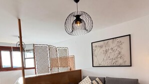 A modern living room with a gray sofa, a white table with chairs, a black pendant light, and a framed abstract art piece on the wall. - Fuente del Tesoro Apartment (AN)