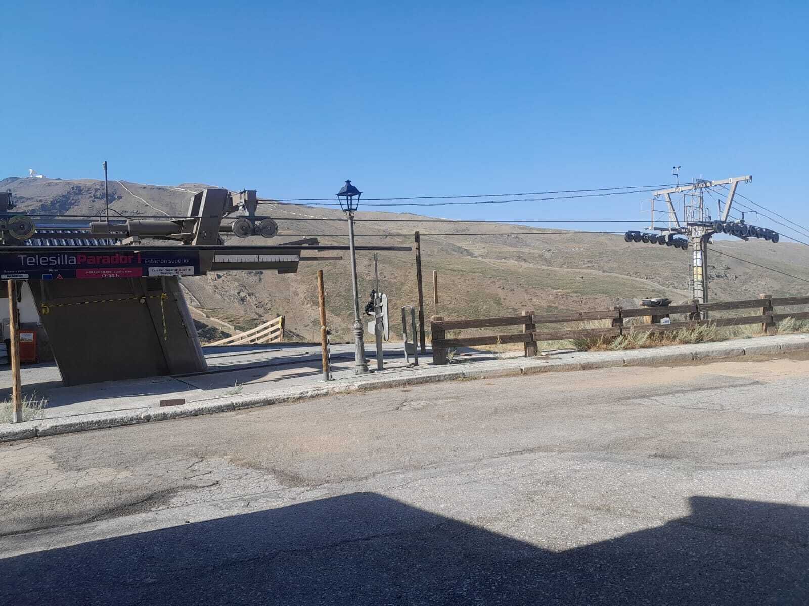 A mountain station with a sign for Telesilla Parador, a wooden fence, and a cable car system.