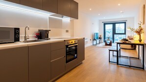 Una cocina moderna con electrodomésticos integrados, un comedor con mesa y sillas, y un amplio ventanal con vistas a la ciudad.