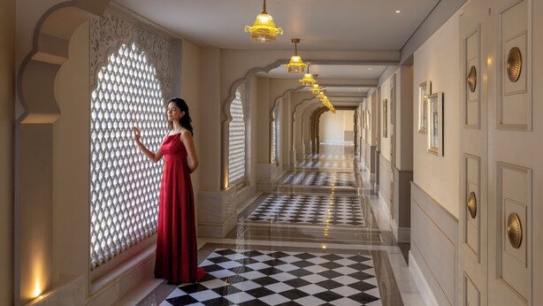 A corridor with patterned walls, chandeliers, and a checkered floor. - Taj Lalit Bagh, Udaipur (Māvli)
