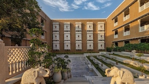 A courtyard with a central staircase, two elephant statues, and a building with multiple balconies. - Taj Lalit Bagh, Udaipur (Māvli)