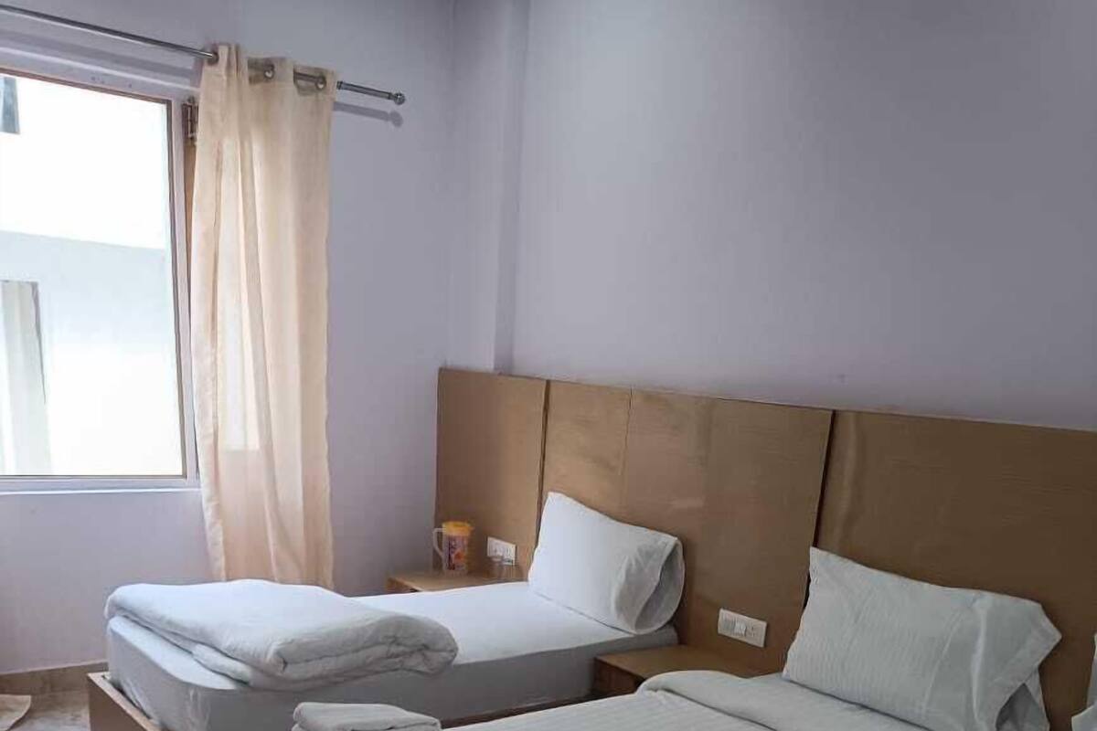 A hotel room with two beds, a red rug, and a window with curtains.