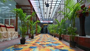 A hotel corridor with a colorful tiled floor, potted plants, and a sign indicating 'ROOMS'. - Mysore Heritage Inn (Mysore)