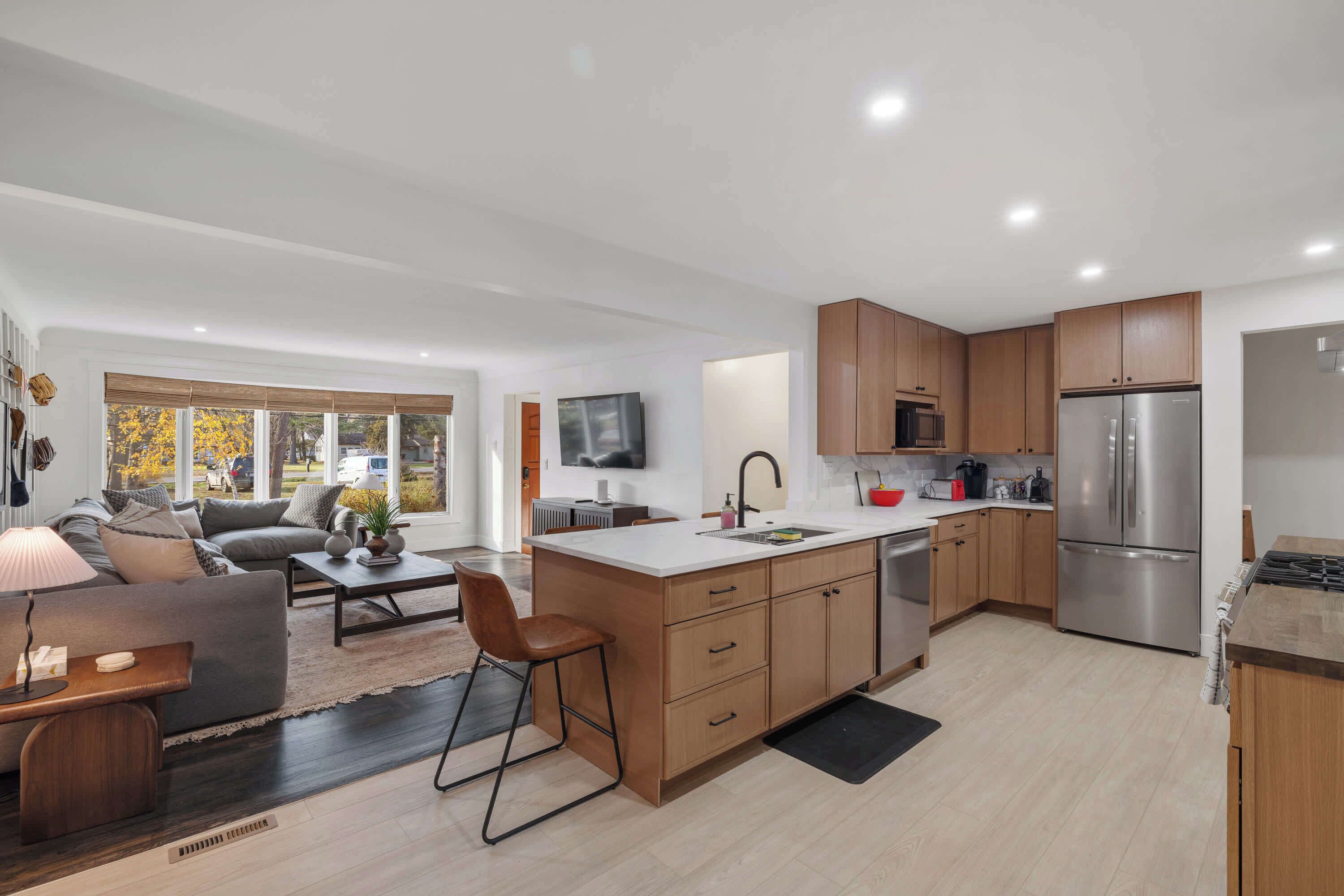 A modern kitchen with wooden cabinets, a stainless steel refrigerator, and a central island.