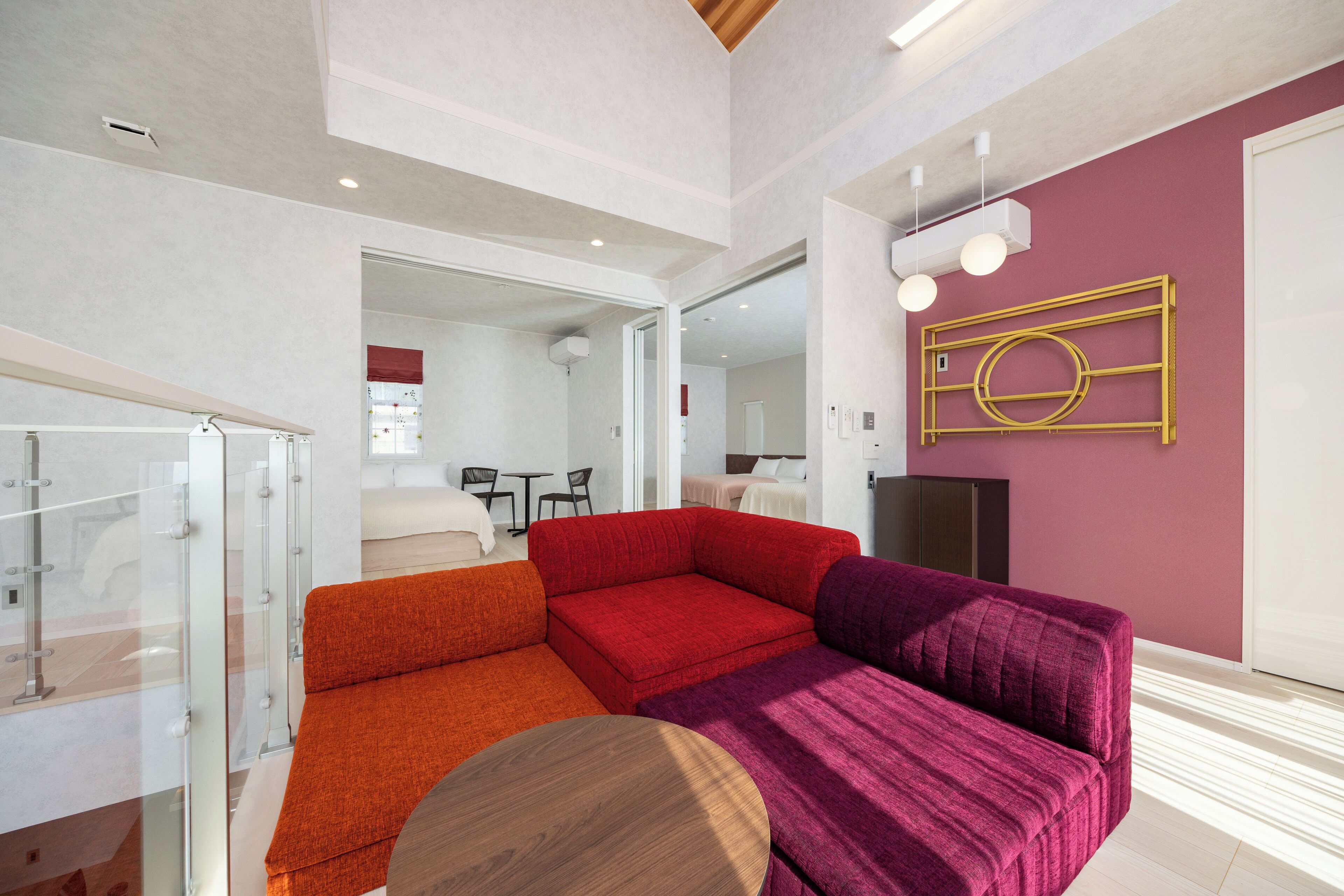 A modern living room with a red and purple sofa set, a wooden coffee table, and a glass partition.