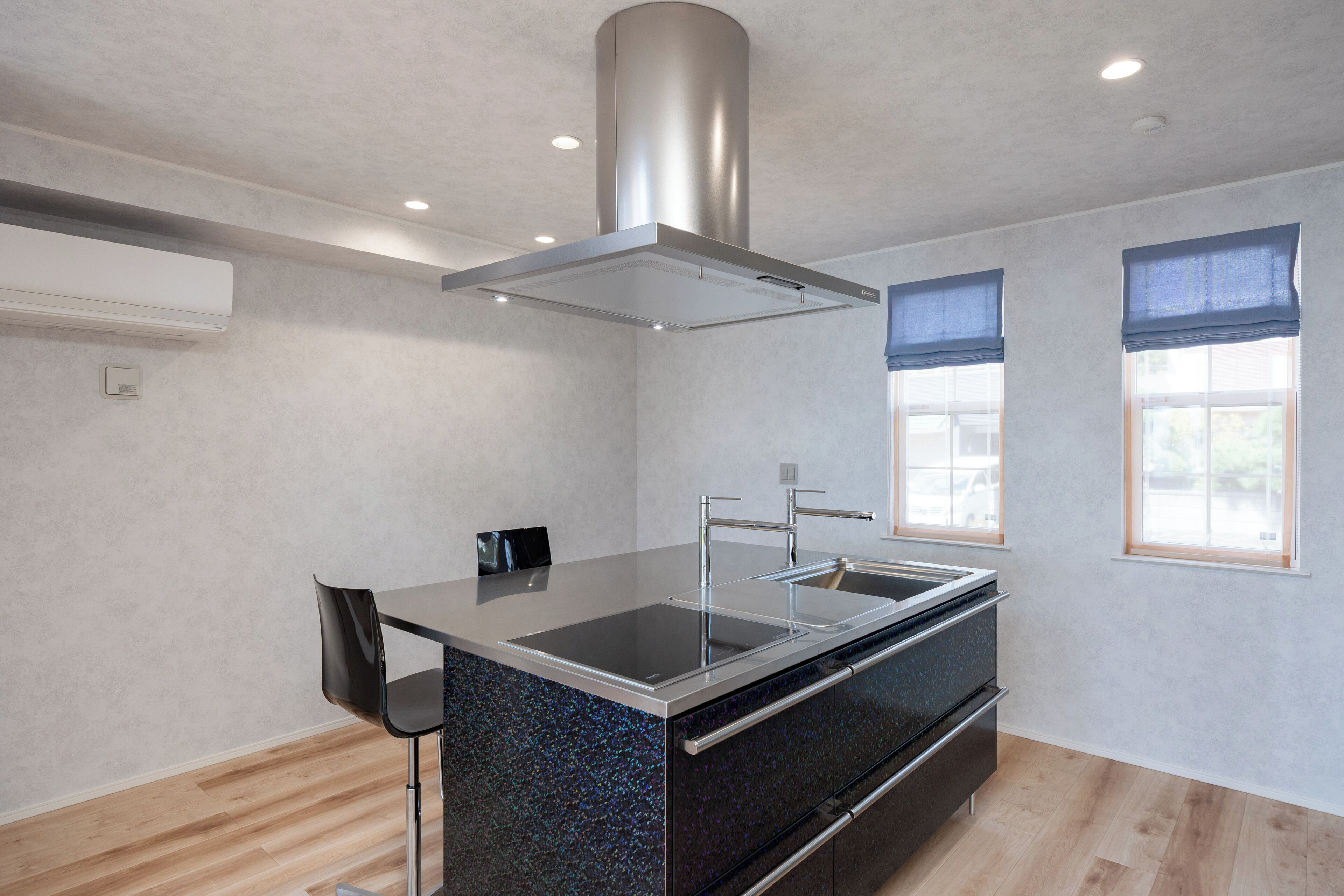 A modern kitchen with a central island, stainless steel appliances, and a built-in oven.