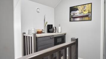 A modern kitchen with a built-in microwave, a coffee maker, and a basket of bread on the counter.