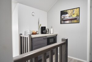 Una cocina moderna con microondas integrado, cafetera y una cesta de pan en la encimera.