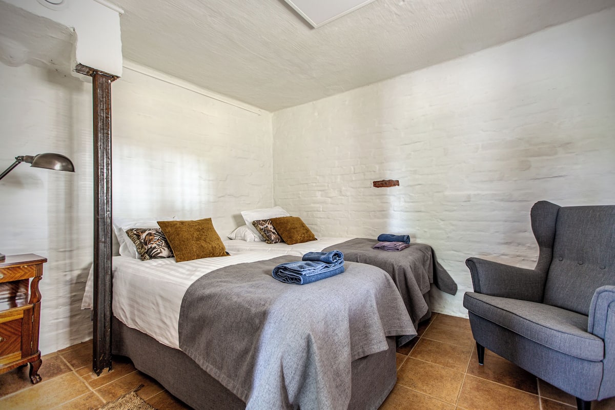 A hotel room with two beds, a chair, and a nightstand.