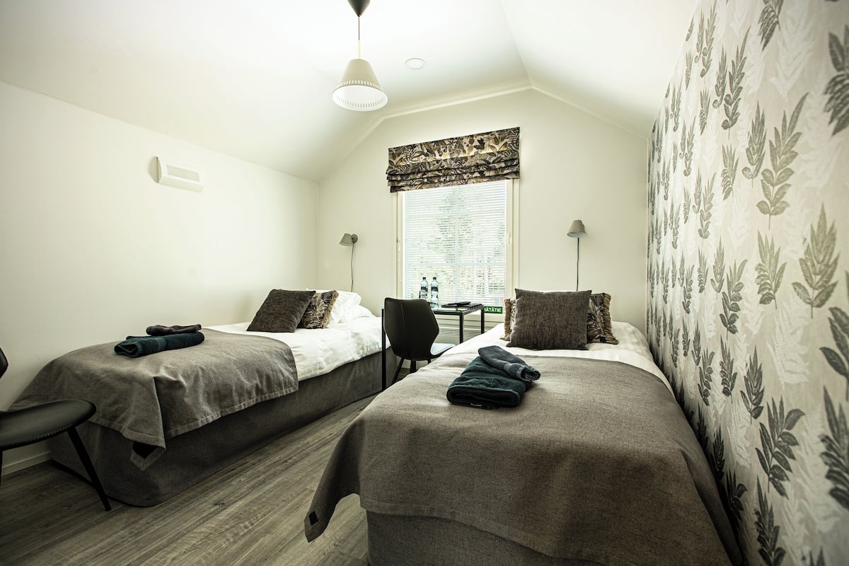 A room with two beds, a desk, and a chair.