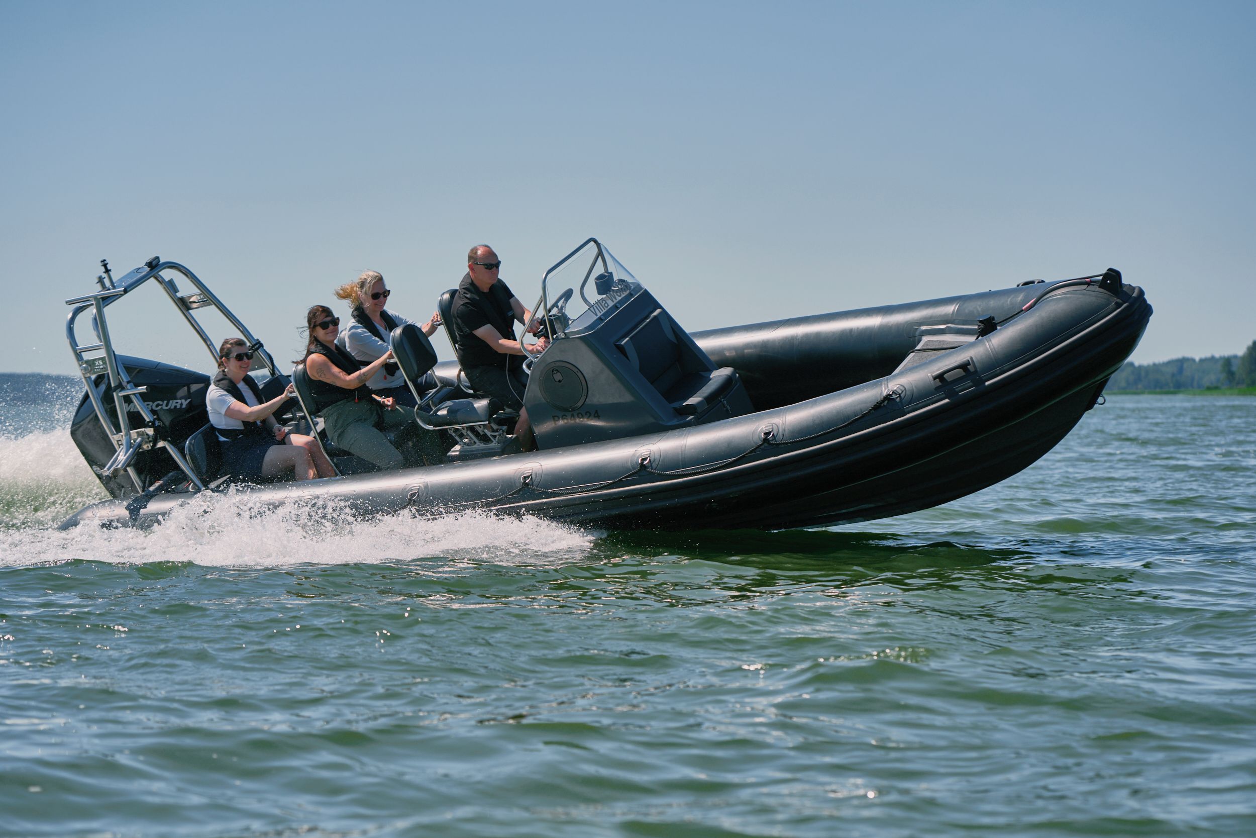 Un bateau à moteur transportant quatre passagers, équipé d’un volant et d’un moteur hors-bord.