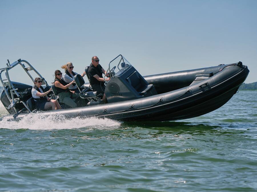 Um barco a motor com quatro passageiros, um leme e um motor de popa.