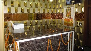 A reception area with a marble counter, decorative wall panels, a television screen, and a ceiling fan. - Dashrath Residency (Ayodhya)