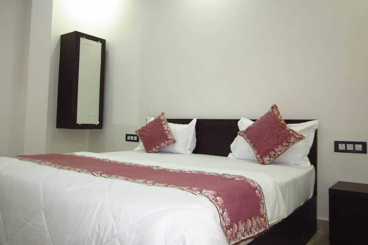 Ein Hotelzimmer mit Bett, Nachttisch, Wandspiegel und Steckdose.