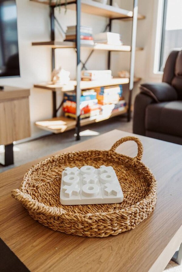 Una cesta tejida con un objeto blanco sobre una mesa de madera en una habitación con una estantería y una silla.
