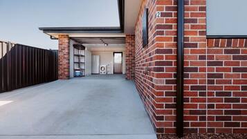 A modern building with a brick exterior, a metal gate, and a concrete driveway leading to a door.