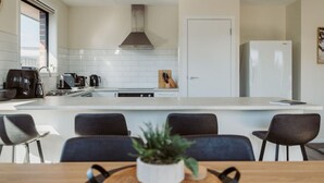 Una cocina moderna con una isla central, armarios blancos y una campana extractora de acero inoxidable.